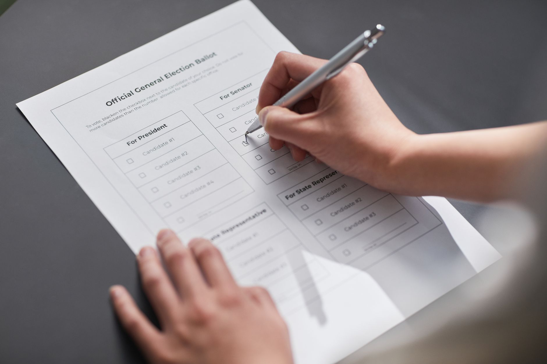 A close-up image of a hand marking an official election ballot with a pen, representing democratic voting.